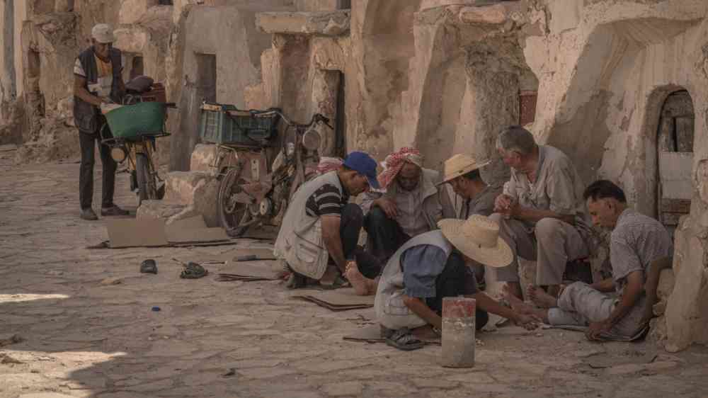 Local men are having a rest at the old building walls during the hot summer day in Medinine, central Tunisia.